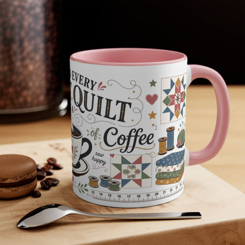 A ceramic coffee mug with a pink handle and interior, featuring a 'Behind Every Great Quilt is a Strong Cup of Coffee' design with sewing motifs and text, styled on a wooden surface with a spoon, coffee beans, and a macaron in the background.