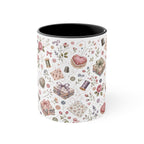 A white ceramic mug with a black interior, decorated with a vintage-style sewing and crafting pattern featuring pink roses, thread spools and fabric. The handle is not visible.