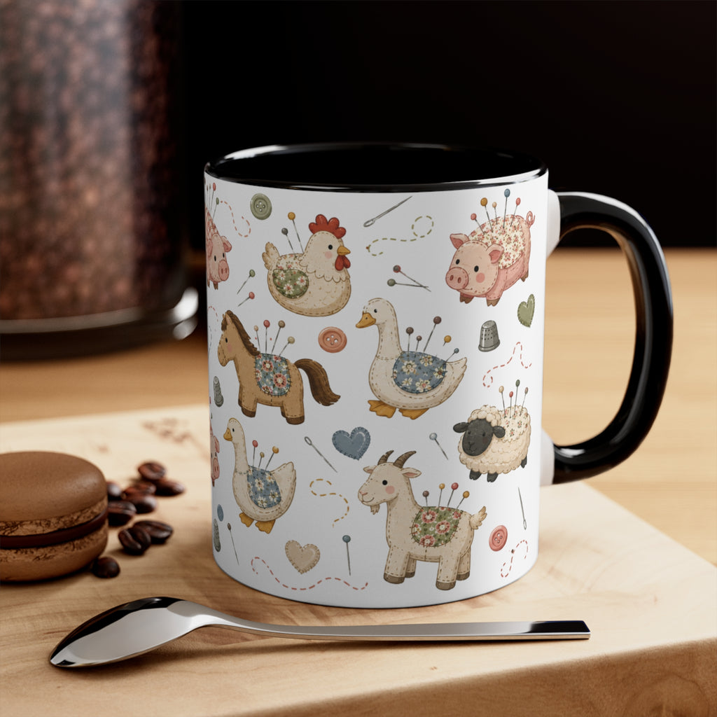 A white ceramic mug with a black handle and interior, decorated with a whimsical pincushion animals including chickens, pigs, ducks, horses, sheep, and goats. The mug is styled on a wooden board with a spoon, coffee beans, and a macaron in the background.