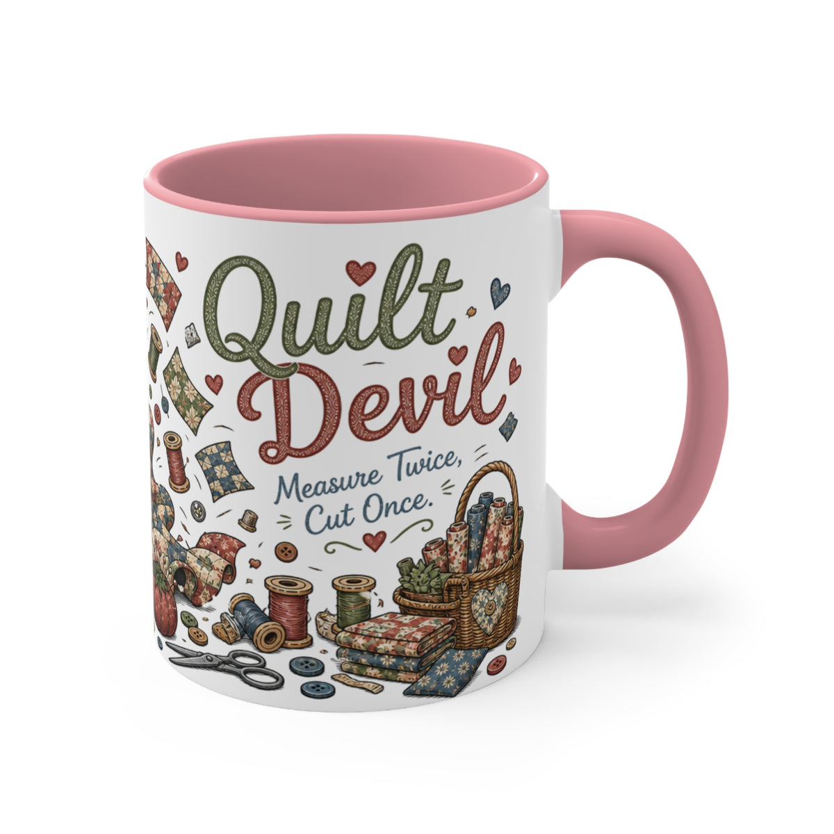 A white ceramic mug with a pink interior and handle, decorated with a vintage-style quilt design featuring the words 'Quilt Devil' and sewing-themed illustrations.