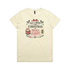 A light butter yellow short-sleeve crewneck t-shirt with a festive Christmas graphic on the front. The graphic features the text 'ALL I WANT FOR CHRISTMAS IS MORE FABRIC' in a mix of black and red fonts, surrounded by illustrations of a ribbon-tied fabric stack, a thread spool, and holly leaves.