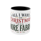 The front of a white ceramic mug with a black interior, featuring a festive Christmas-themed graphic that reads 'ALL I WANT FOR CHRISTMAS IS MORE FABRIC' in dark green and red lettering with small decorative accents.