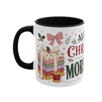 The left side of a white ceramic mug with a black handle and interior, decorated with a bundle of fabric, a pink ribbon, thread spool and holly. The text 'All I Want for Christmas is More Fabric' is partially visible.