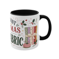 The right side of a white ceramic mug with a black handle and interior, decorated with a bundle of fabric, a pincushion and holly. The text 'All I Want for Christmas is More Fabric' is partially visible.