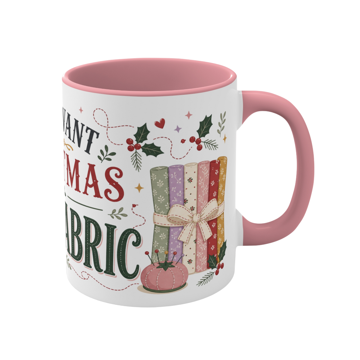 The right side of a white ceramic mug with a pink handle and interior, decorated with a bundle of fabric, a pink ribbon, thread spool, a pincushion and holly. The text 'All I Want for Christmas is More Fabric' is partially visible.
