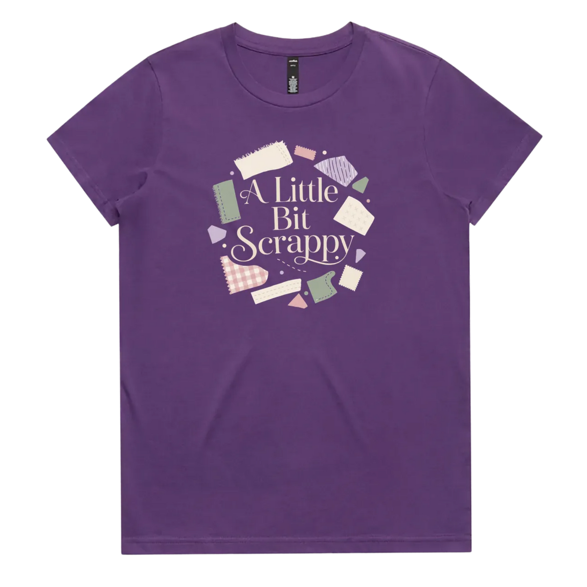 A purple short-sleeve crewneck t-shirt featuring a circular graphic on the chest with the text 'A Little Bit Scrappy' surrounded by small colorful fabric pieces.