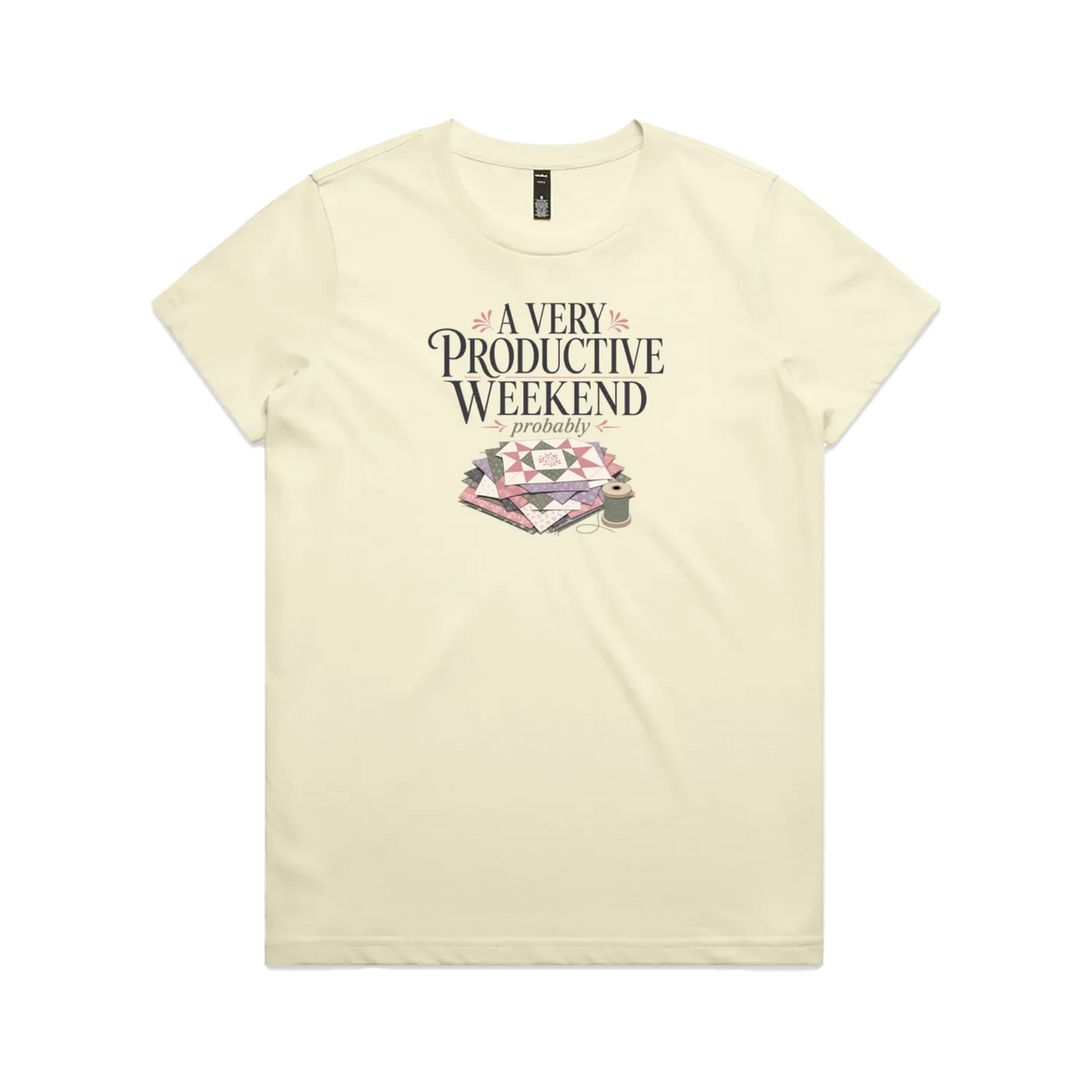 A pale butter yellow short-sleeve graphic t-shirt featuring the words 'A Very Productive Weekend, probably' above a stack of patchwork blocks and a thread spool.