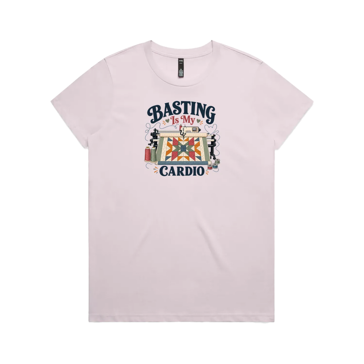 A pale mauve short-sleeve t-shirt featuring the words 'Basting Is My Cardio' with an illustration of a longarm quilting machine, a quilt and thread.