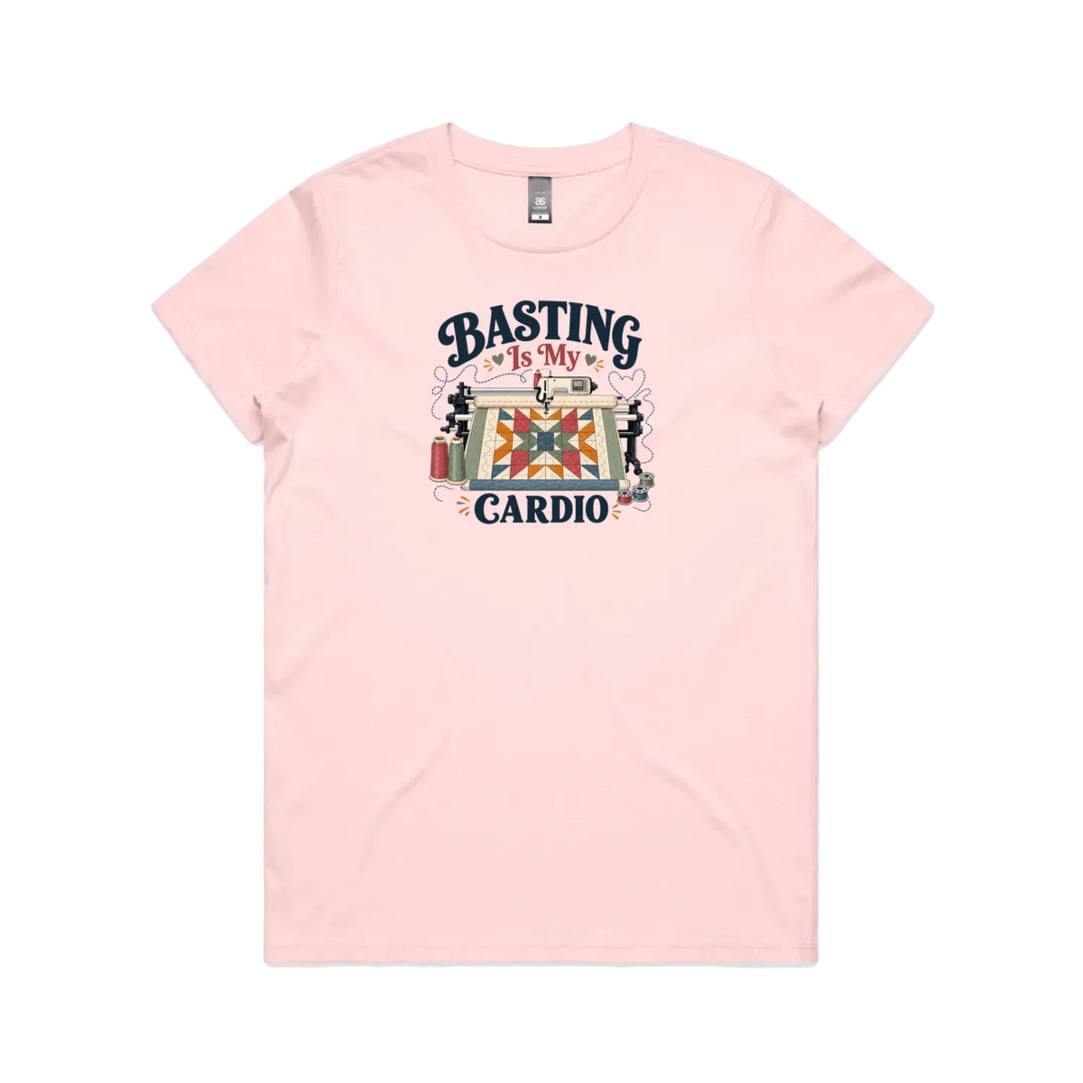 A pale pink short-sleeve t-shirt featuring the words 'Basting Is My Cardio' with an illustration of a longarm quilting machine, a quilt and thread.