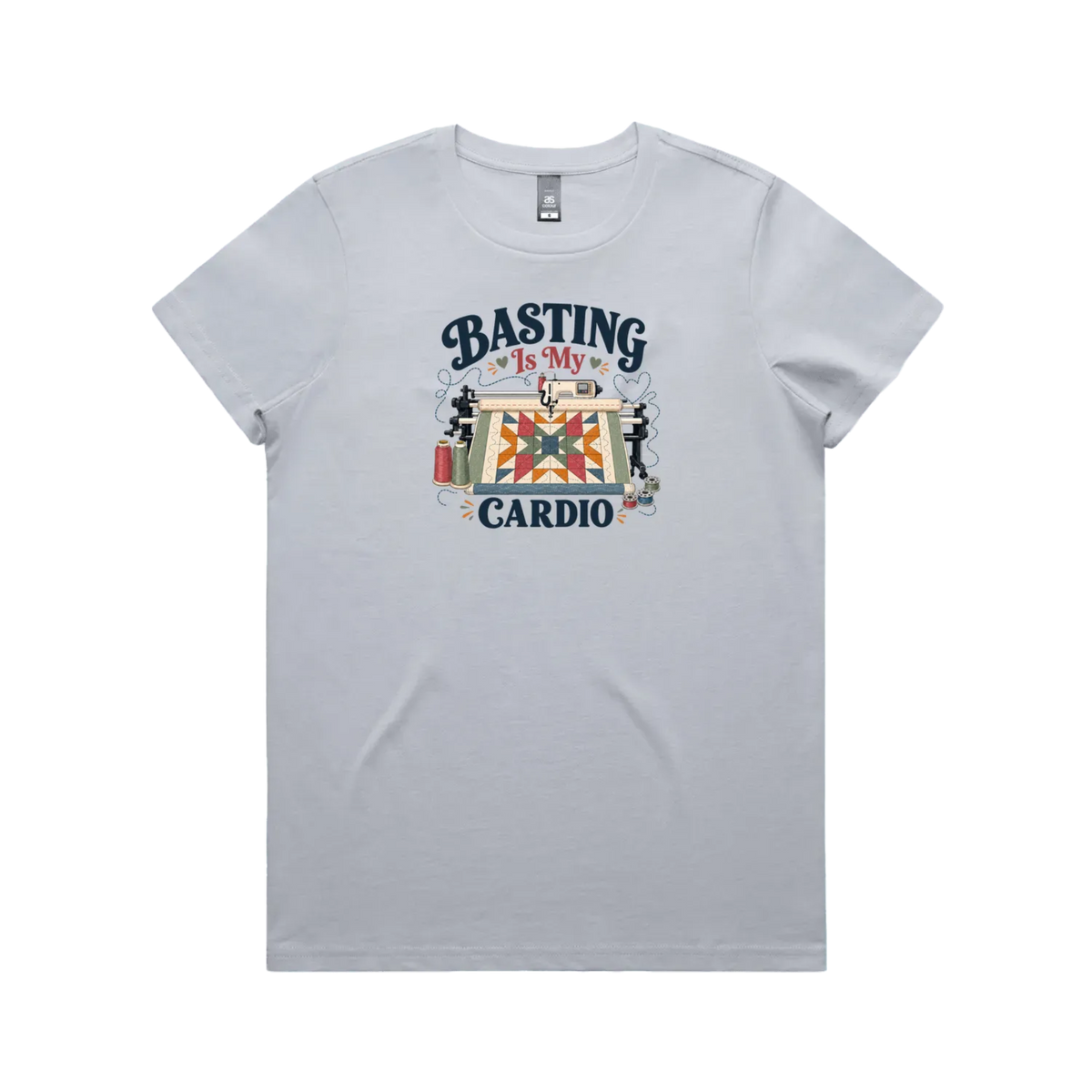 A powder blue short-sleeve t-shirt featuring the words 'Basting Is My Cardio' with an illustration of a longarm quilting machine, a quilt and thread.