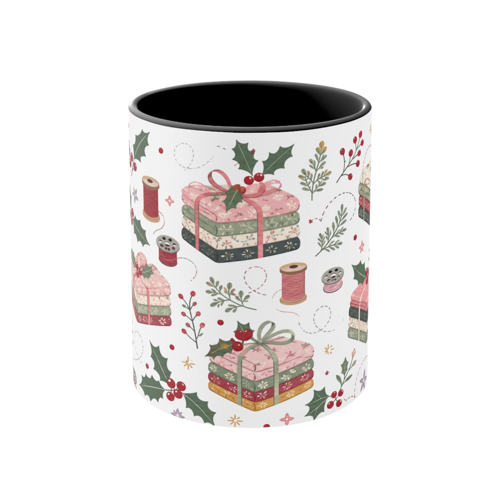The front of a white ceramic mug with a black interior, decorated with a repeating pattern of stacked fabrics, holly leaves, berries, and thread spools in soft pink, green, beige, and brown tones.