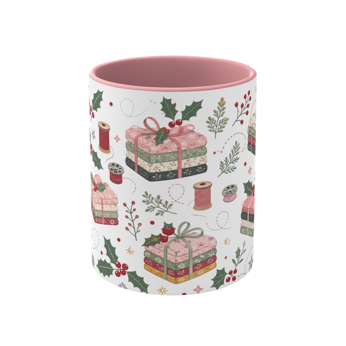 The front of a white ceramic mug with a pink interior, decorated with a repeating pattern of stacked fabrics, holly leaves, berries, and thread spools in soft pink, green, beige, and brown tones.