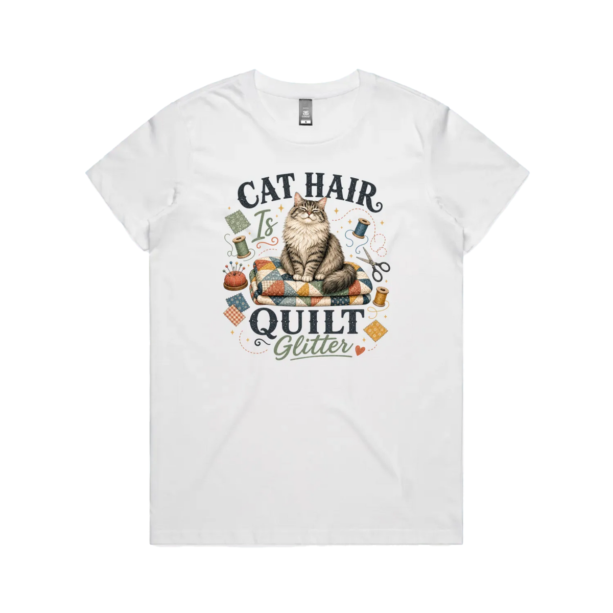 A white short-sleeve t-shirt with the words 'Cat Hair is Quilt Glitter' around an illustration of a cat sitting on a quilt surrounded by sewing accessories.