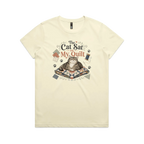A pale butter yellow short-sleeve t-shirt with an illustration of a cat sitting on a quilt surrounded by sewing accessories and the words 'The Cat Sat on My Quilt'.