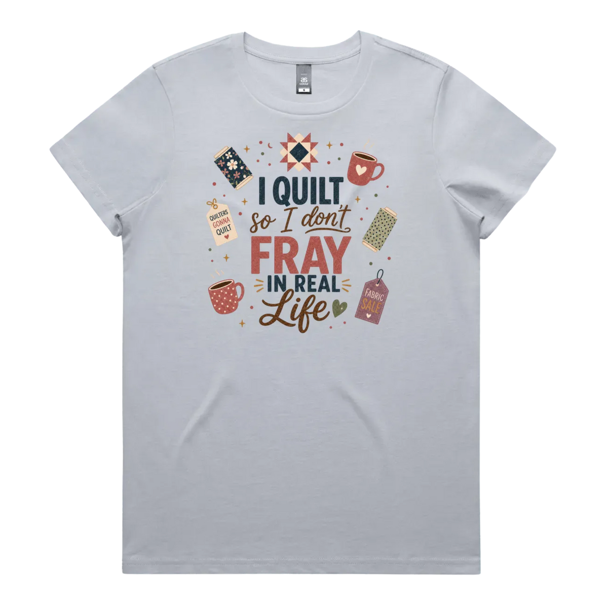 A powder blue short-sleeve crewneck t-shirt featuring a colorful graphic print on the front with quilting-themed illustrations and the text 'I Quilt So I Don't Fray in Real Life'.