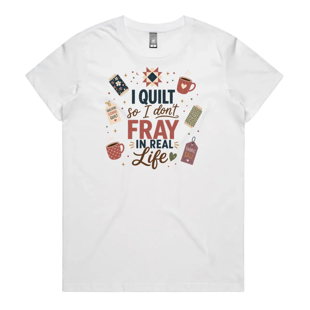 A white short-sleeve crewneck t-shirt featuring a colorful graphic print on the front with quilting-themed illustrations and the text 'I Quilt So I Don't Fray in Real Life'.