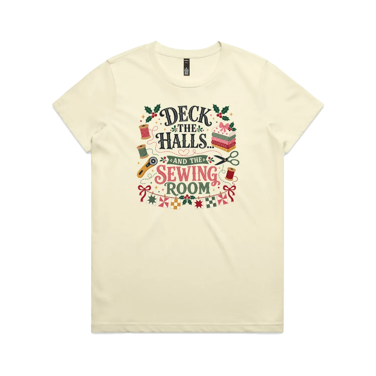 A pale butter yellow short-sleeve crewneck t-shirt featuring a colorful graphic print on the front with sewing-themed illustrations and the text 'Deck the Halls and the Sewing Room'.