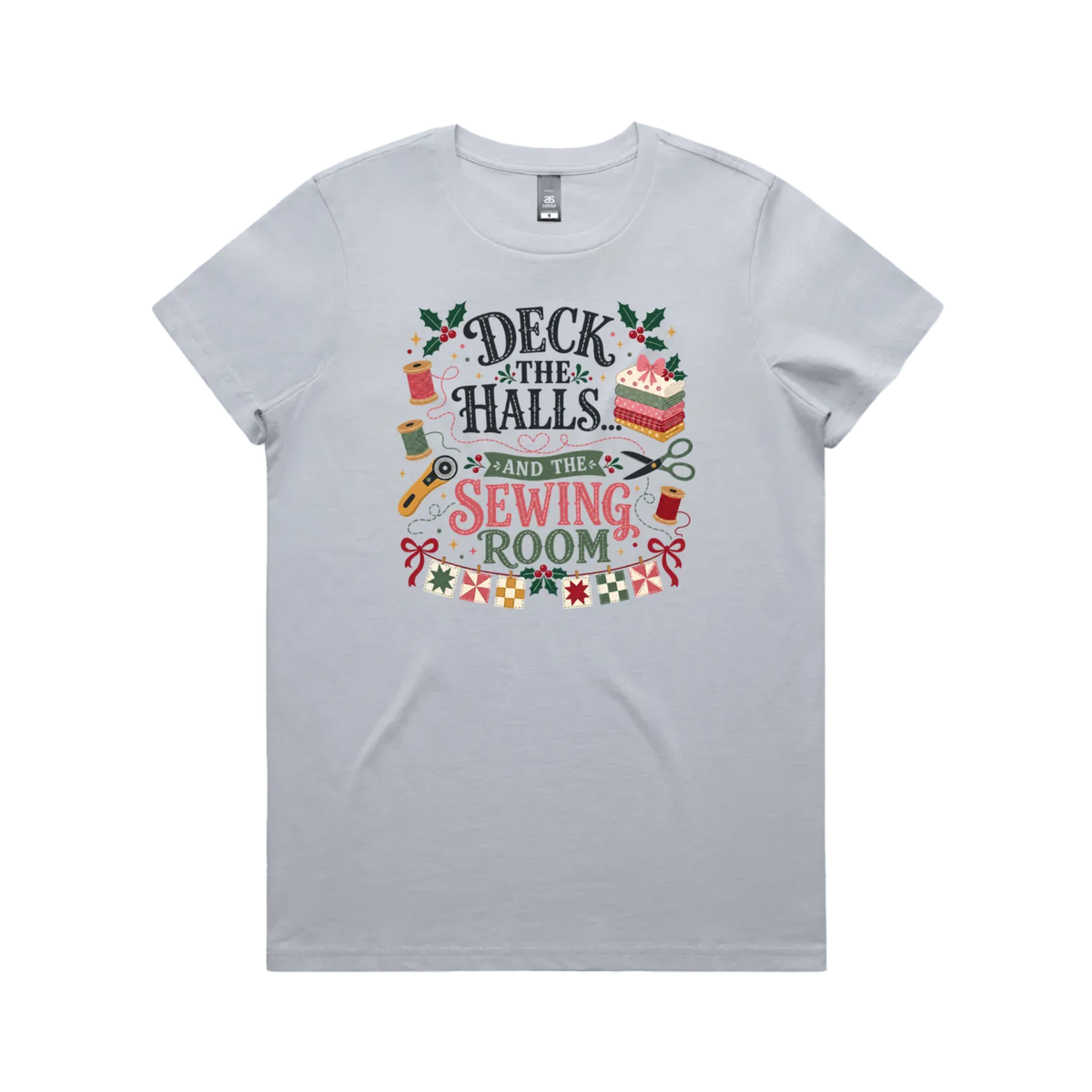 A powder blue short-sleeve crewneck t-shirt featuring a colorful graphic print on the front with sewing-themed illustrations and the text 'Deck the Halls and the Sewing Room'.