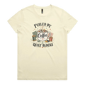 A pale butter yellow short-sleeve t-shirt with a vintage-style graphic on the front that reads 'Fueled by Coffee & Quilt Blocks' around an illustration of a coffee mug, quilting thread spools, and fabric.