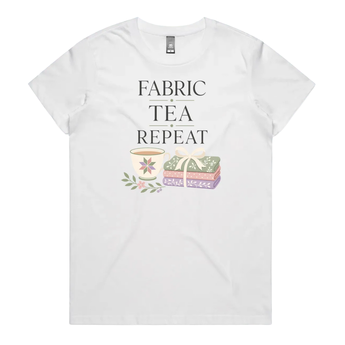 A white short-sleeve crewneck t-shirt featuring a graphic print that reads 'FABRIC, TEA, REPEAT' above an illustration of a teacup, floral details, and patterned fabric stack.