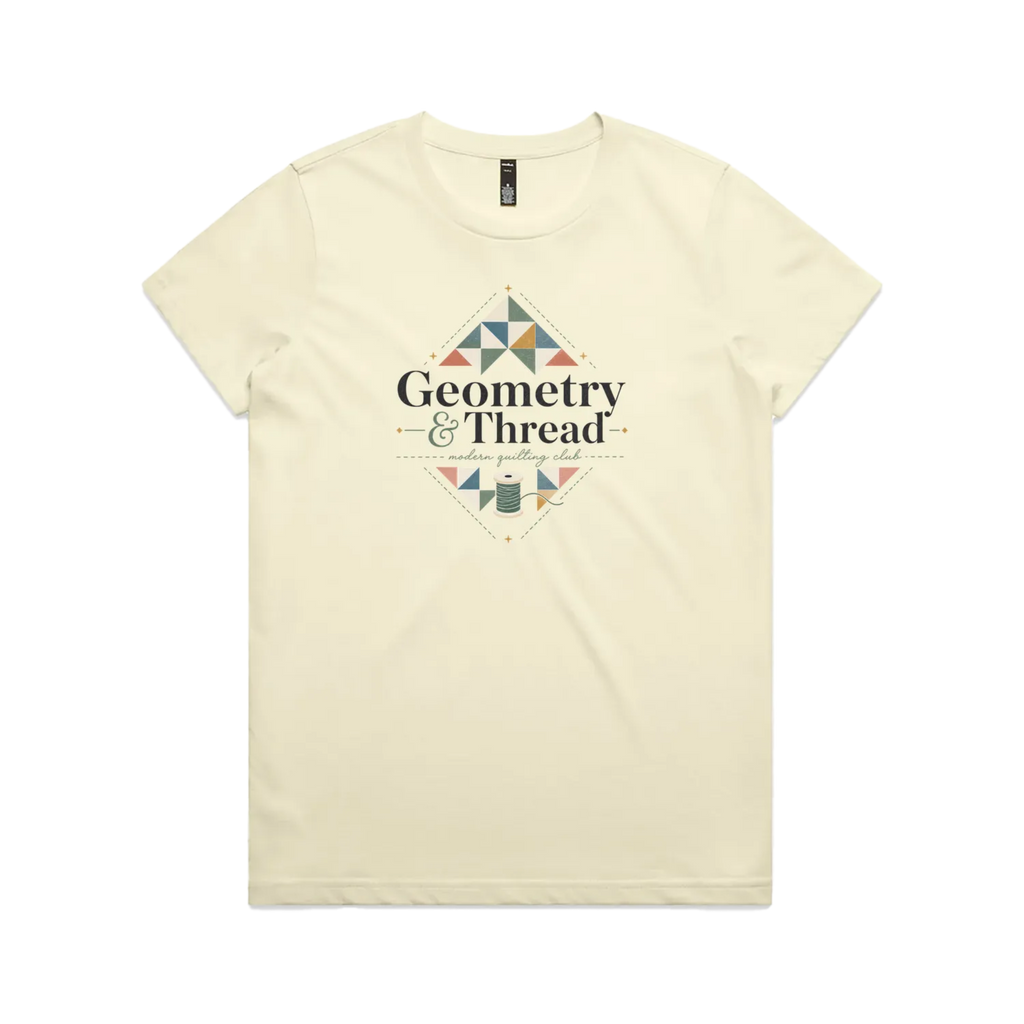 A pale butter yellow short-sleeve crewneck graphic t-shirt featuring the words 'Geometry & Thread, Modern Quilting Club' surrounded by patchwork triangles and a spool of thread.