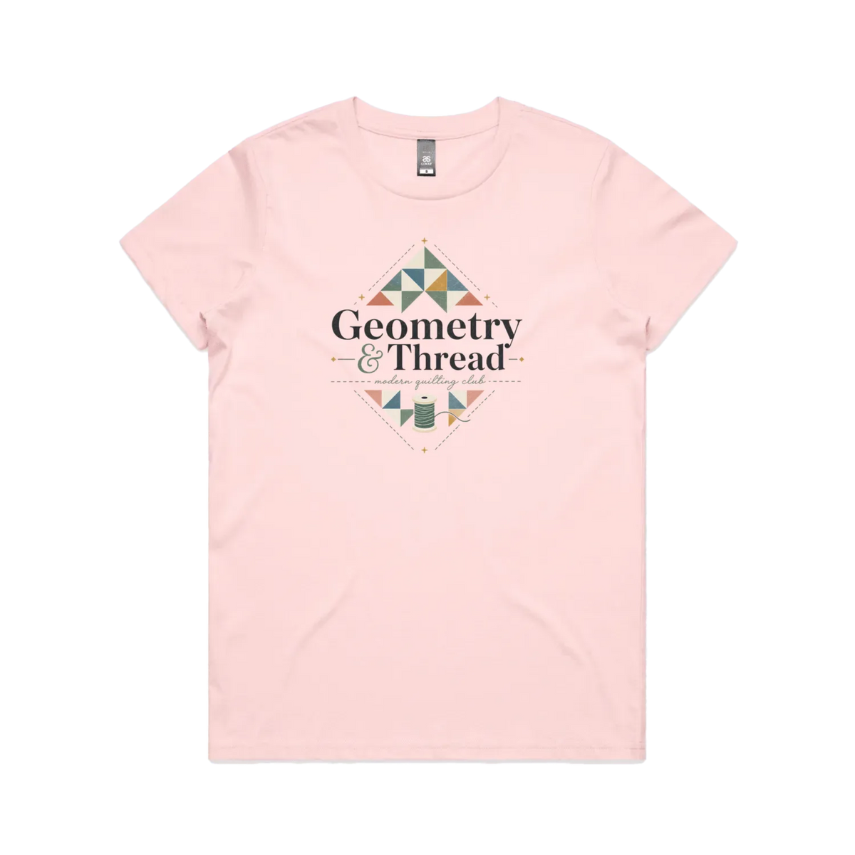 A pale pink short-sleeve crewneck graphic t-shirt featuring the words 'Geometry & Thread, Modern Quilting Club' surrounded by patchwork triangles and a spool of thread.
