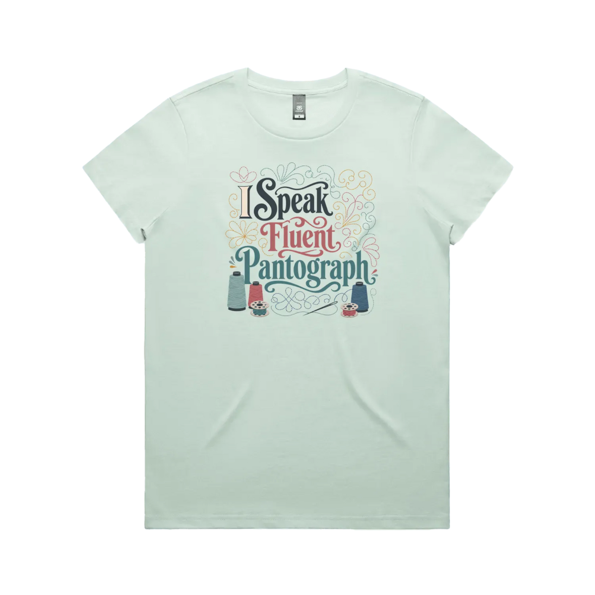 A pale mint green graphic short-sleeve t-shirt with the words 'I Speak Fluent Pantrograph' surrounded by thread spools, bobbins, a needle and swirling stitche lines in multi colours.
