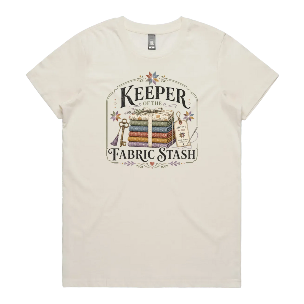 A cream crewneck, short-sleeved t-shirt with the vintage style graphic 'Keeper of the Fabric Stash'.