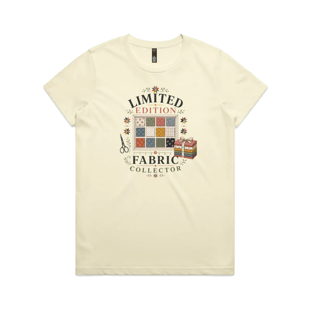 A pale butter yellow short-sleeve crewneck t-shirt featuring the text 'Limited Edition Fabric Collector' surround a fabric swatch board, a tied bundle of fabric and scissors.