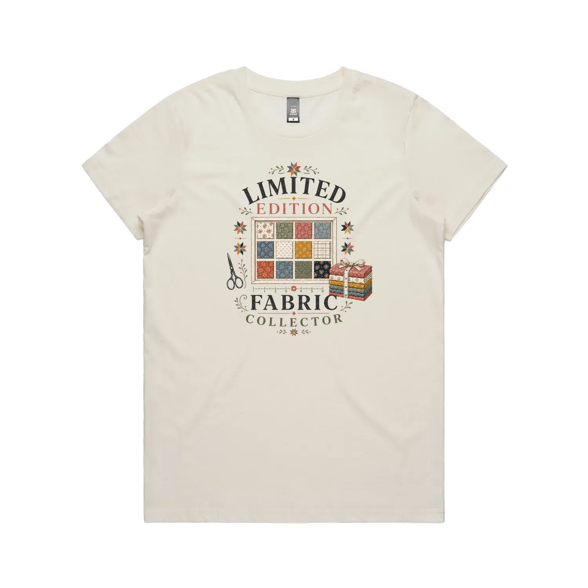 An off-white short-sleeve crewneck t-shirt featuring the text 'Limited Edition Fabric Collector' surround a fabric swatch board, a tied bundle of fabric and scissors.