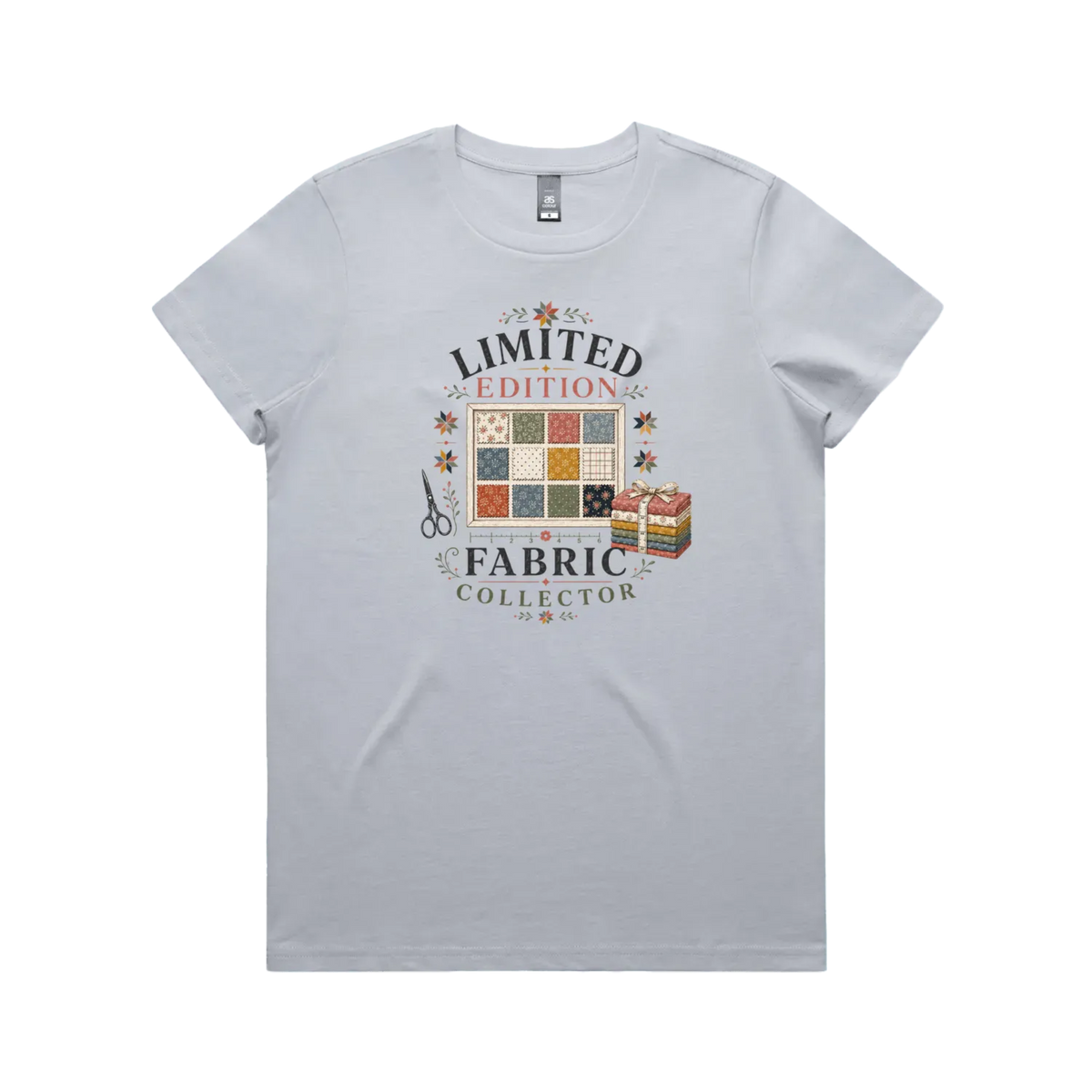 A powder blue short-sleeve crewneck t-shirt featuring the text 'Limited Edition Fabric Collector' surround a fabric swatch board, a tied bundle of fabric and scissors.