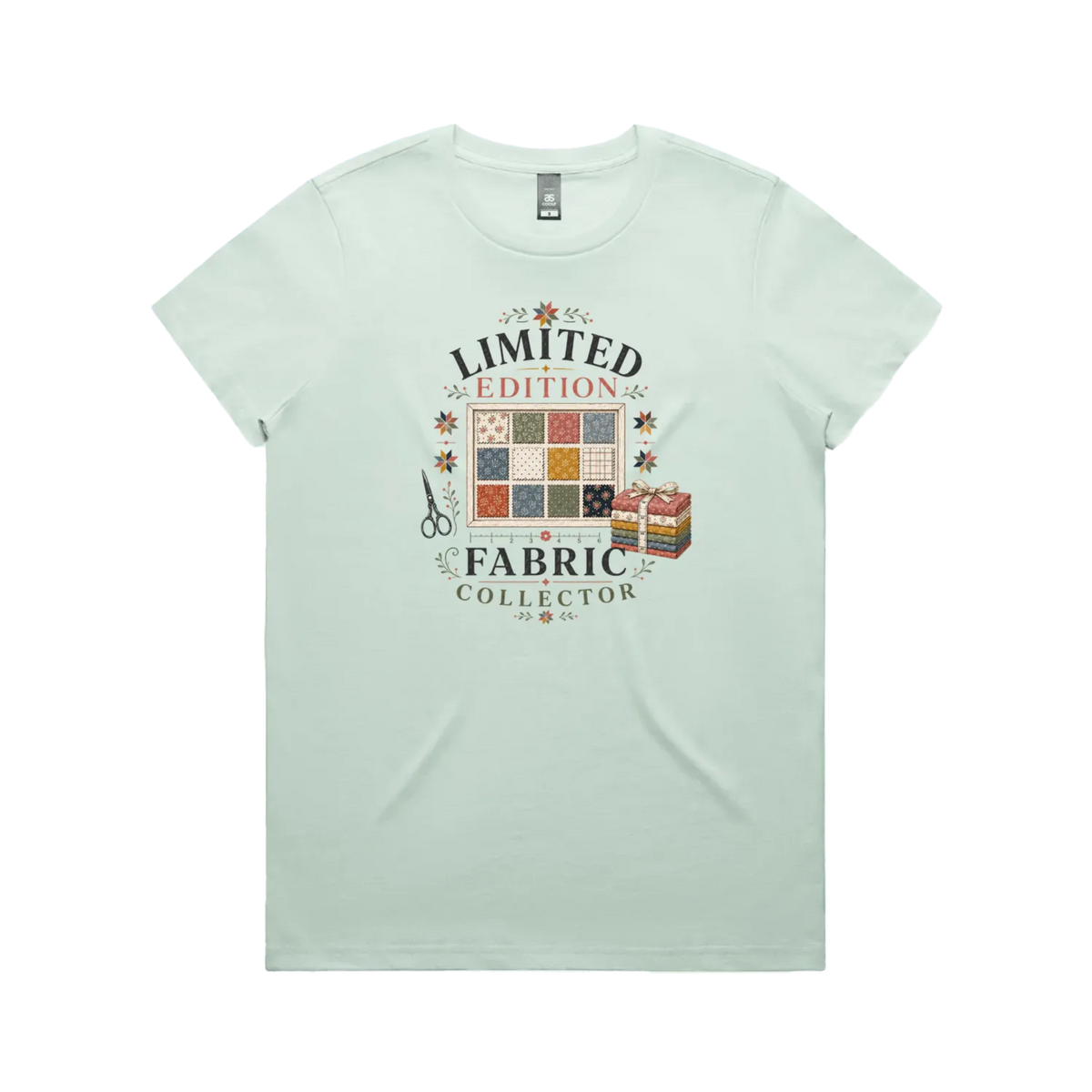 A pale mint green short-sleeve crewneck t-shirt featuring the text 'Limited Edition Fabric Collector' surround a fabric swatch board, a tied bundle of fabric and scissors.