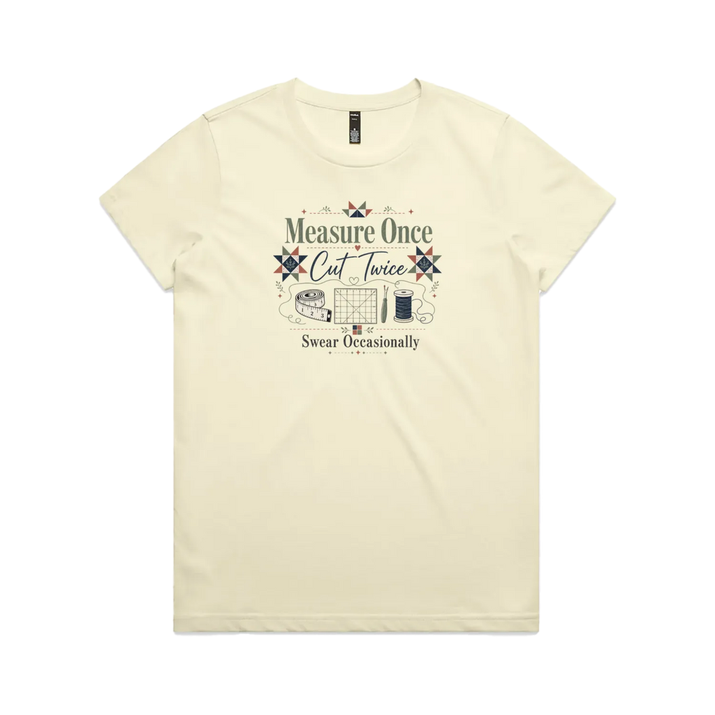 A pale butter yellow short-sleeve crewneck t-shirt with the graphic 'Measure Once, Cut Twice, Swear Occasionally'. The design includes patchwork stars and quilting accessories.
