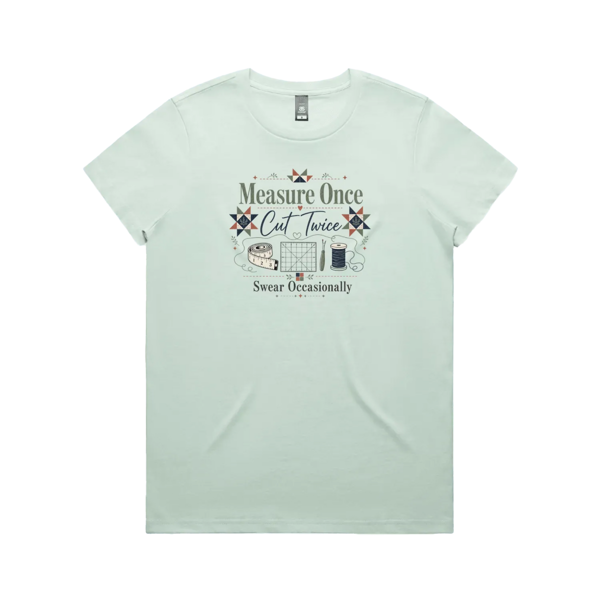 A pale mint green short-sleeve crewneck t-shirt with the graphic 'Measure Once, Cut Twice, Swear Occasionally'. The design includes patchwork stars and quilting accessories.