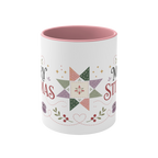 The front of a white ceramic mug with a pink interior decorated with a festive quilt star, stitch lines, leaves and berries.