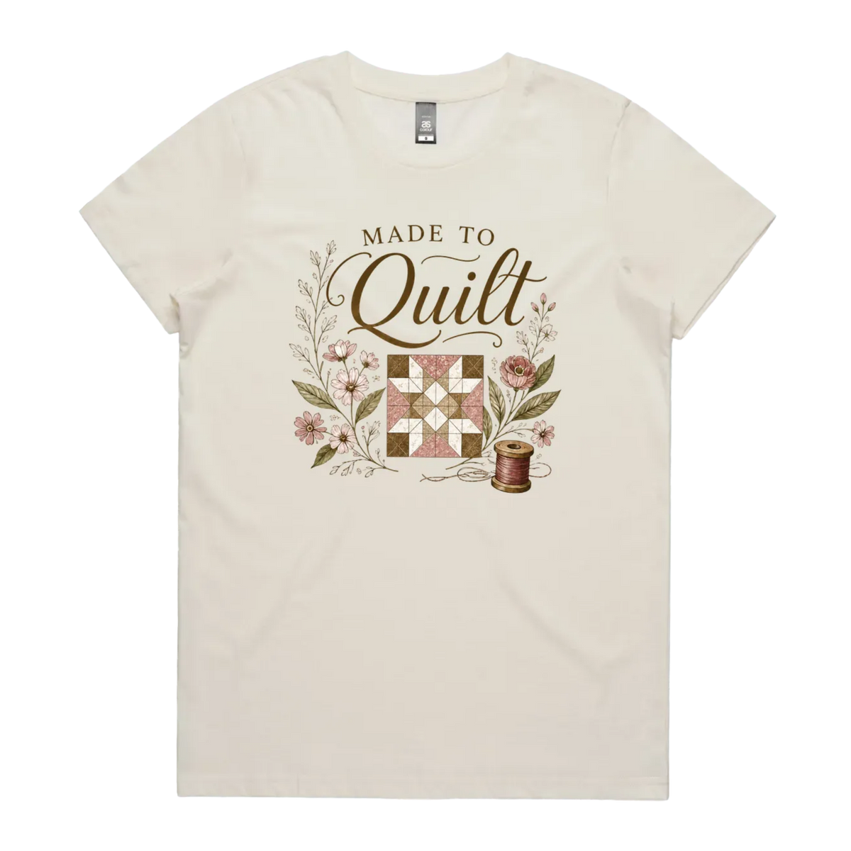 A light cream short-sleeve crewneck t-shirt featuring a vintage-style quilt graphic with the text 'Made To Quilt' in brown script and floral illustrations.
