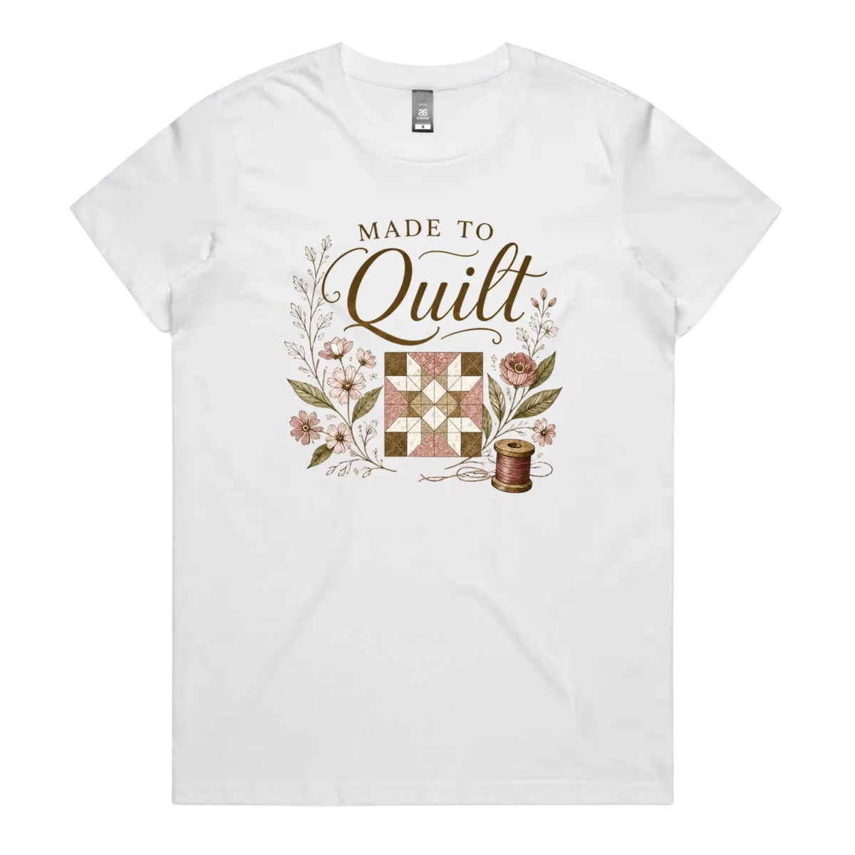 A white short-sleeve crewneck t-shirt featuring a vintage-style quilt graphic with the text 'Made To Quilt' in brown script and floral illustrations.