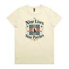 A light butter yellow short-sleeve t-shirt with a colorful graphic on the front that reads 'Nine Lives, Nine Patches' around a nine patch quilt block with a black cat silhouette in the middle.
