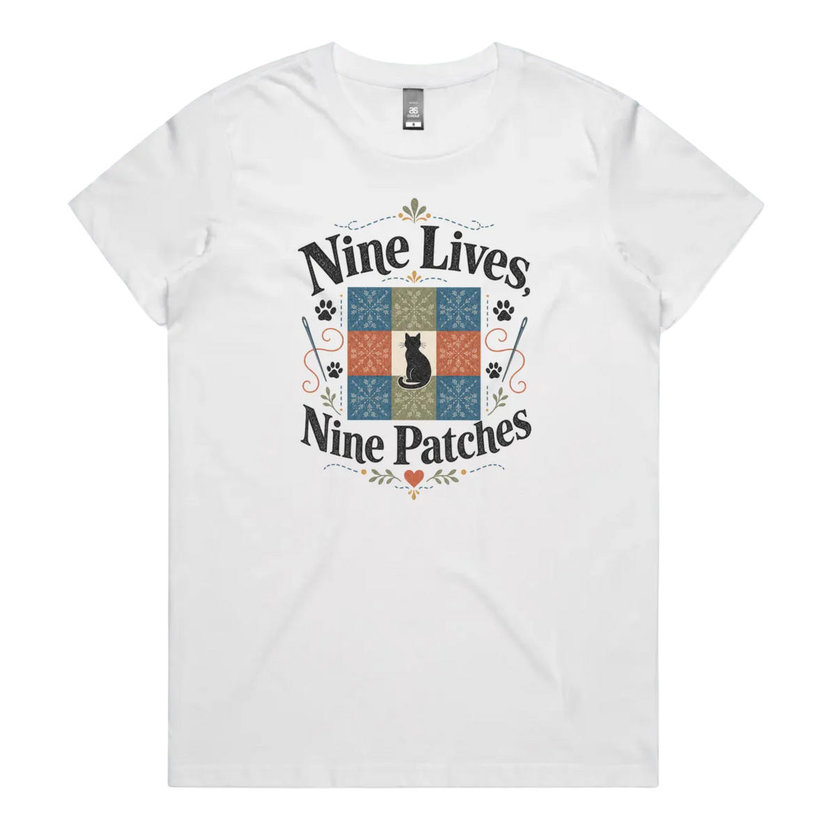 A white short-sleeve t-shirt with a colorful graphic on the front that reads 'Nine Lives, Nine Patches' around a nine patch quilt block with a black cat silhouette in the middle.