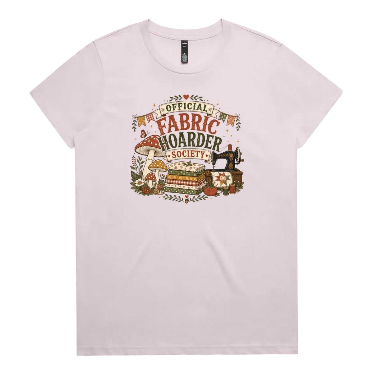 A pale mauve crewneck short-sleeved t-shirt with the words 'Official Fabric Hoarder Society' above an illustration of a stack of fabric, a sewing machine and a group of muchrooms, flowers and a snail.