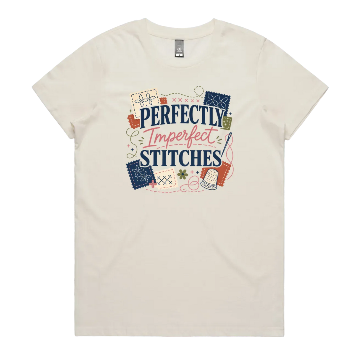 A pale cream short-sleeve crewneck t-shirt featuring a colorful graphic print on the front with the text 'Perfectly Imperfect Stitches' surrounded by sashiko-themed illustrations.