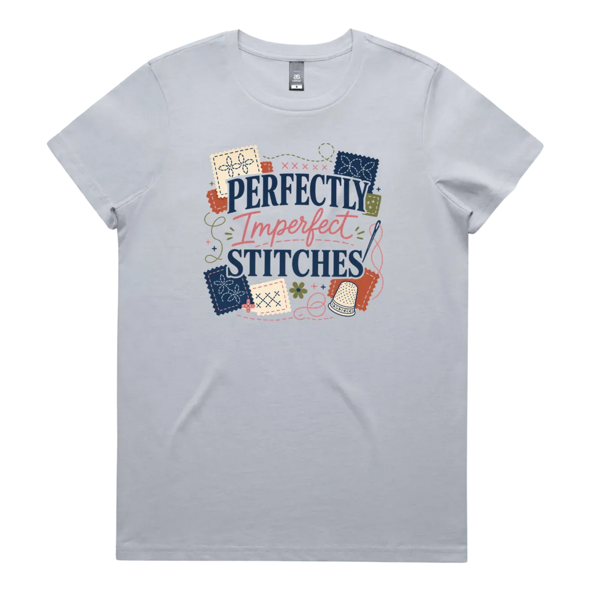 A pale powder blue short-sleeve crewneck t-shirt featuring a colorful graphic print on the front with the text 'Perfectly Imperfect Stitches' surrounded by sashiko-themed illustrations.