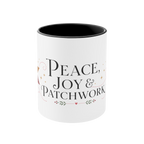 The front of a white ceramic mug with a black interior, featuring a festive Christmas-themed graphic that reads ‘Peace, Joy & Patchwork' in black lettering with small decorative accents.