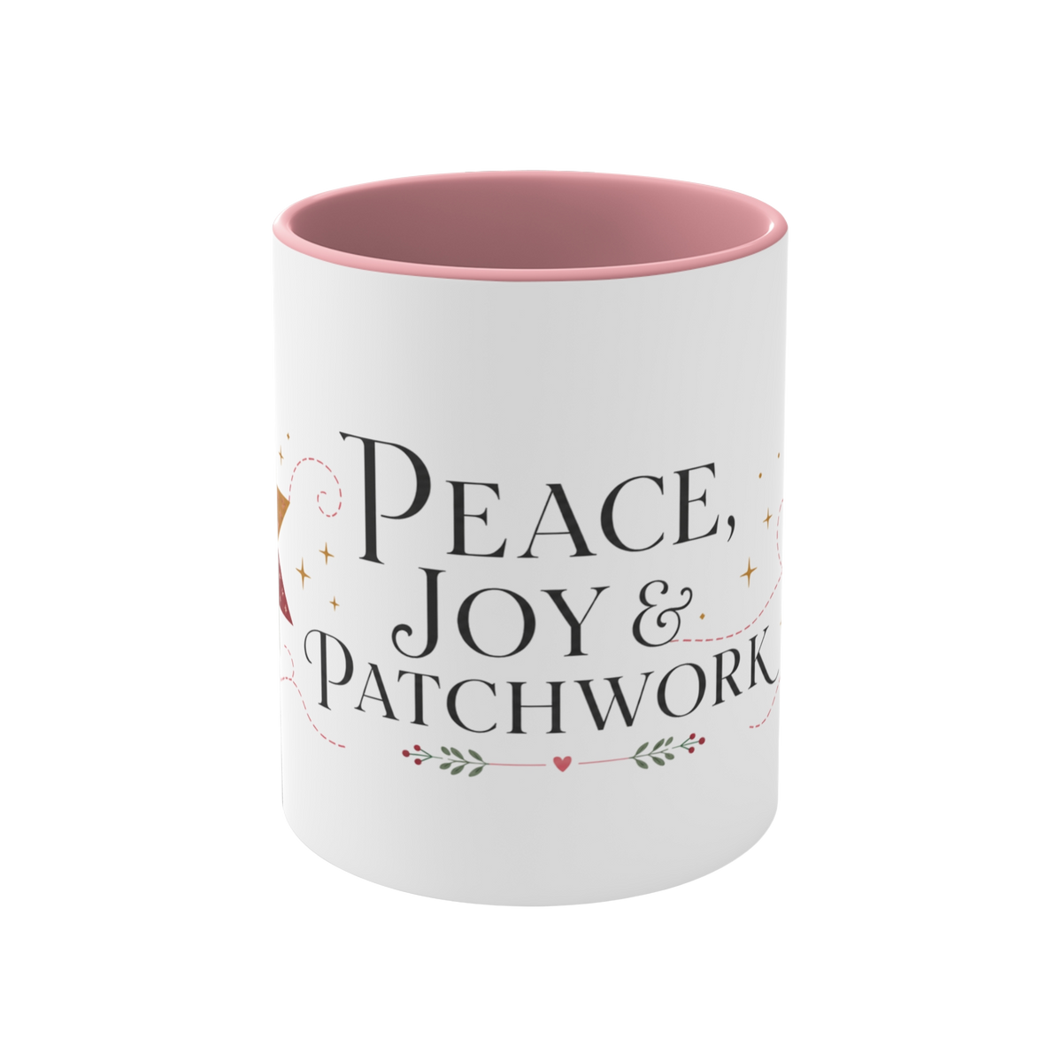 The front of a white ceramic mug with a pink interior and rim, showing the words ‘Peace, Joy & Patchwork'. The text is styled in black fonts with small heart and leaf accents.