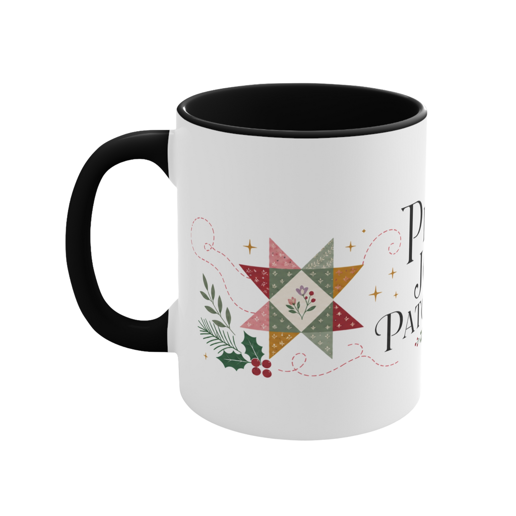 The left side of a white ceramic mug with a black handle and interior, decorated with a quilt block, stitch lines and holly. The text ‘Peace, Joy & Patchwork' is partially visible.