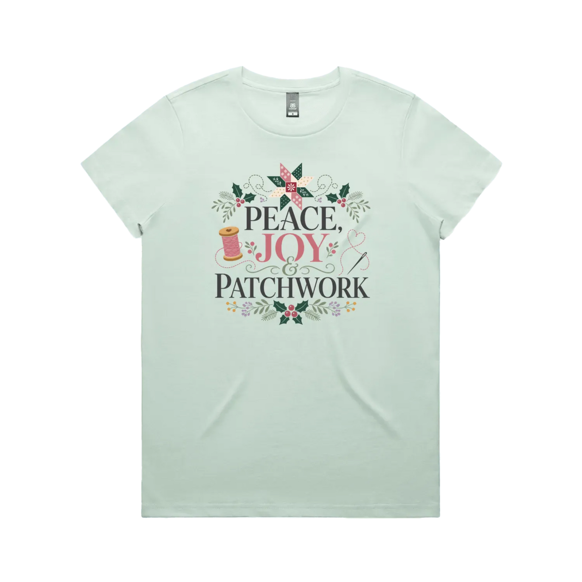 A light seafoam green short-sleeve crewneck t-shirt with a central graphic print that reads 'Peace, Joy & Patchwork' in dark lettering, decorated with a pink bow, quilt block, spool of thread, needle, and floral elements.
