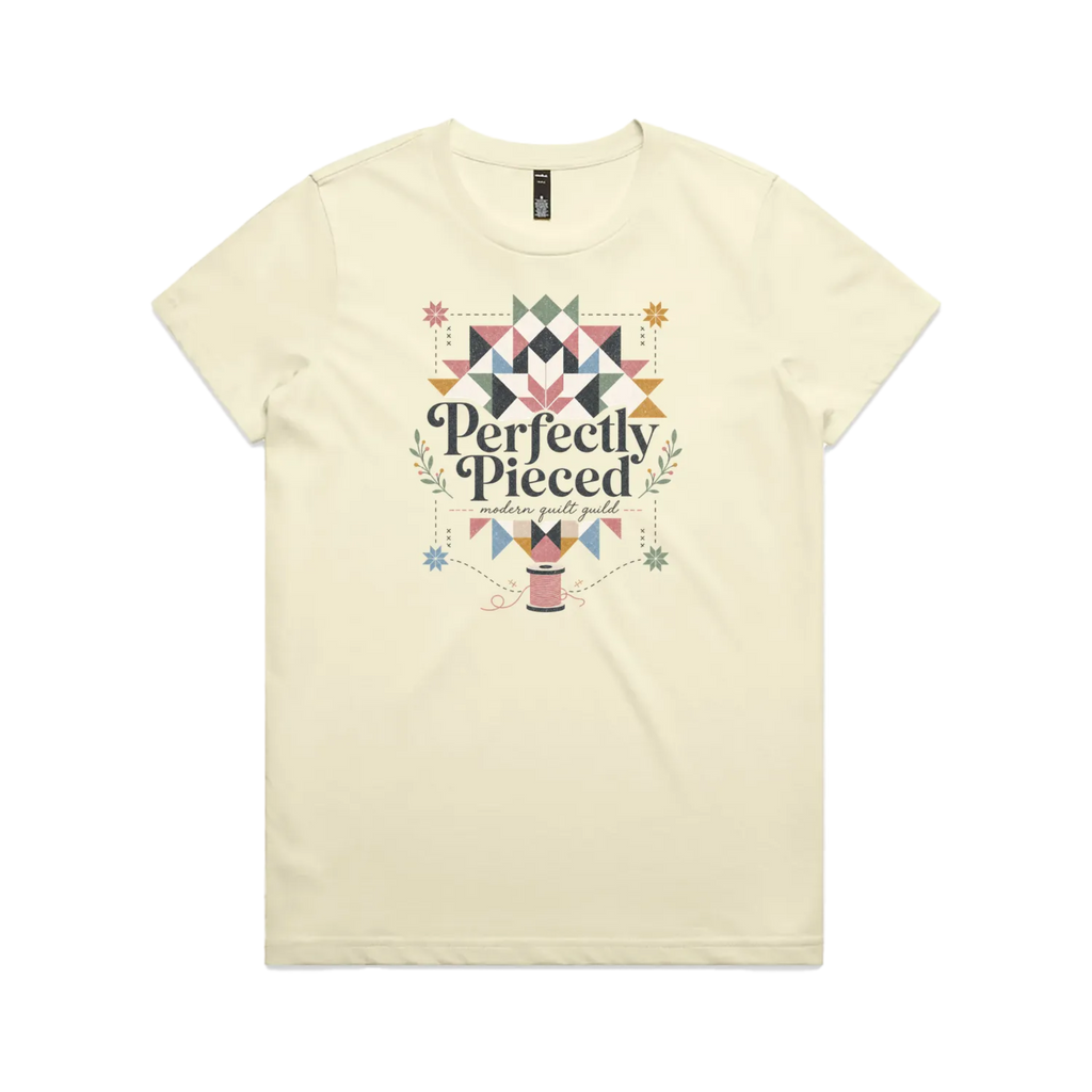 A pale butter yellow graphic short-sleeve t-shirt with the words 'Perfectly Pieced Modern Quilt Guild' cutting through a large patchwork star.