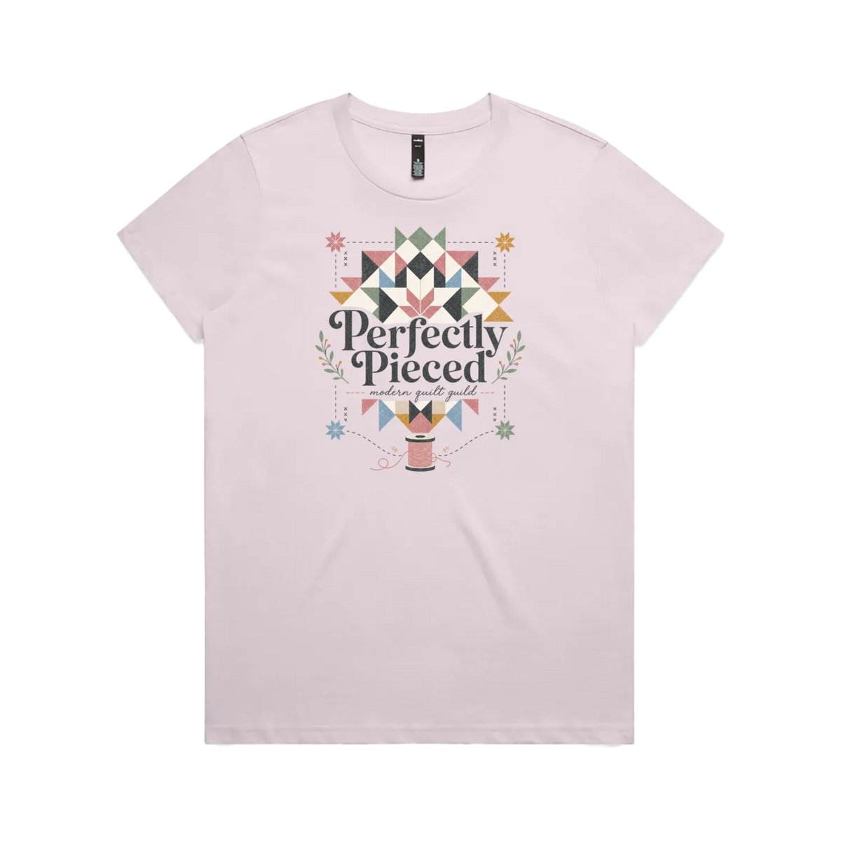 A pale mauve graphic short-sleeve t-shirt with the words 'Perfectly Pieced Modern Quilt Guild' cutting through a large patchwork star.
