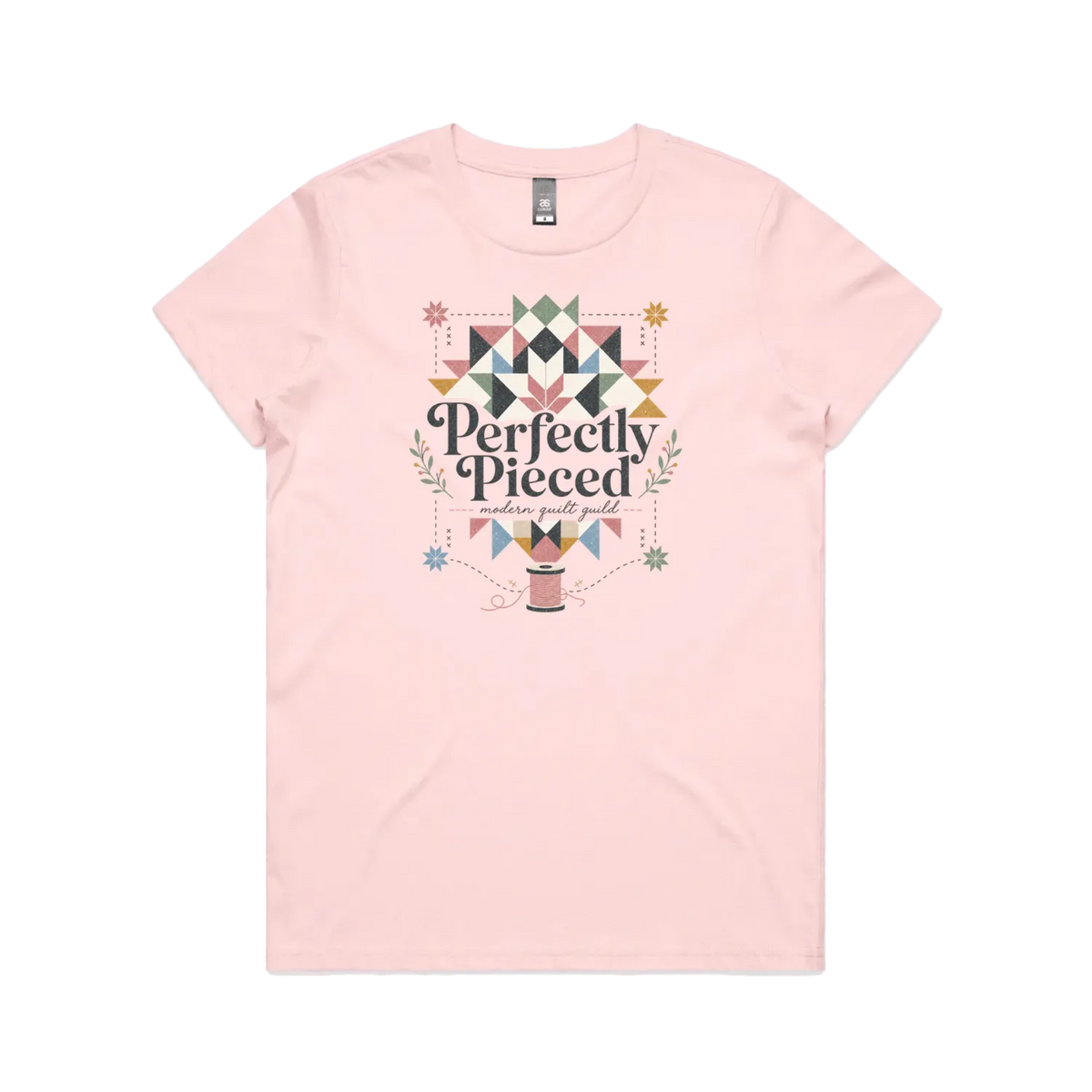 A pale pink graphic short-sleeve t-shirt with the words 'Perfectly Pieced Modern Quilt Guild' cutting through a large patchwork star.