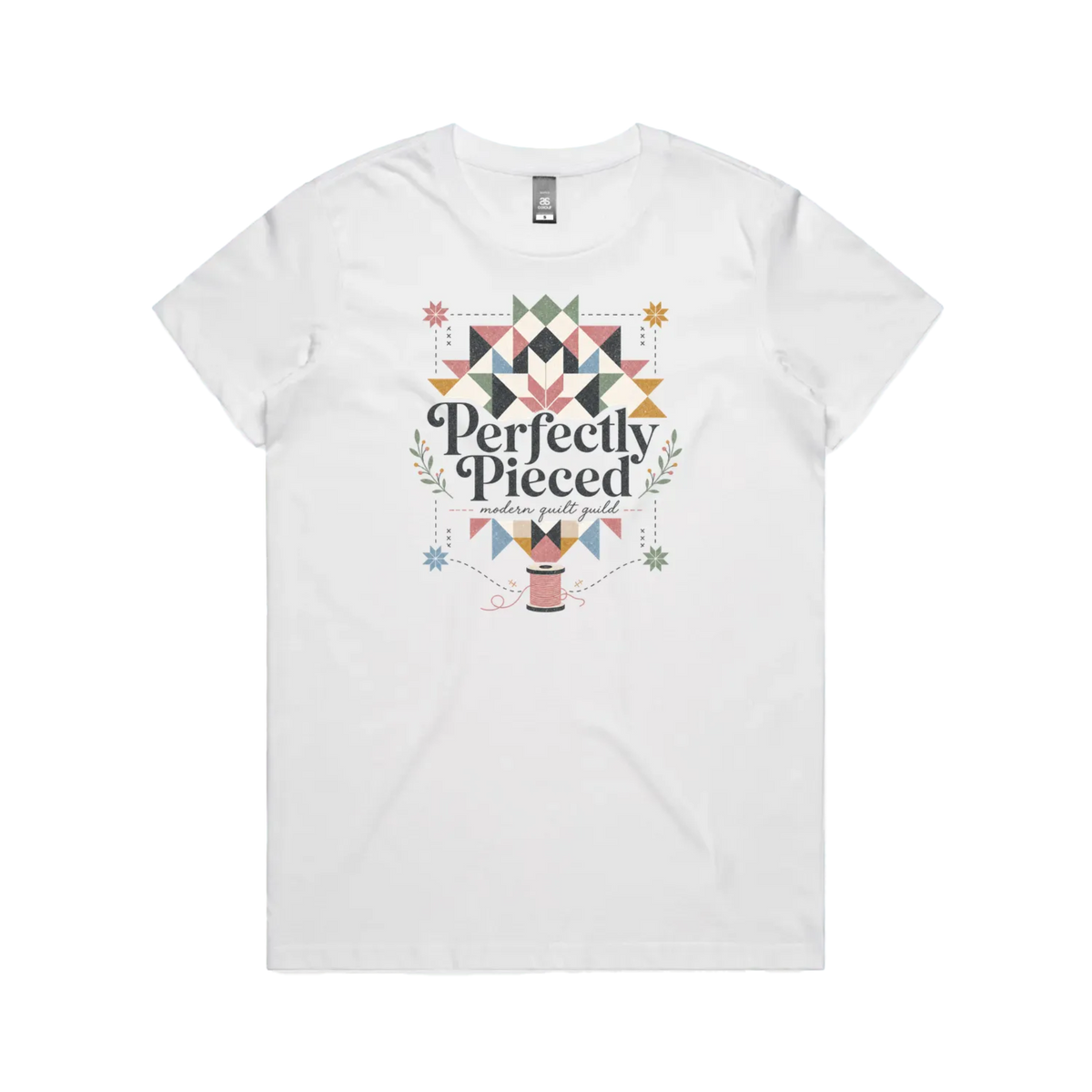 A white graphic short-sleeve t-shirt with the words 'Perfectly Pieced Modern Quilt Guild' cutting through a large patchwork star.